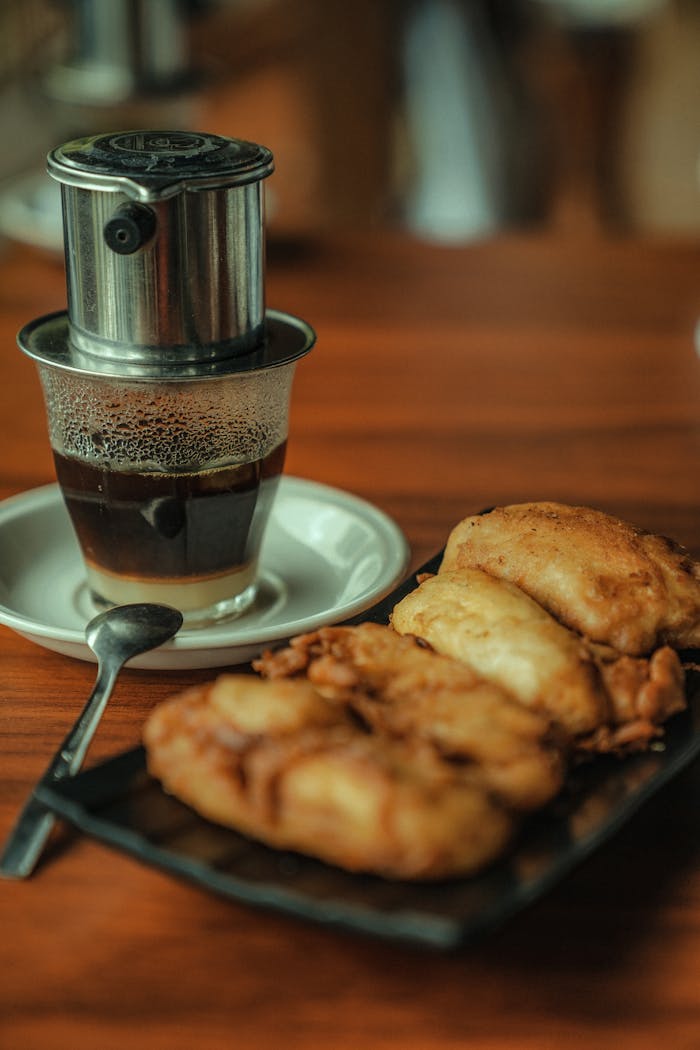 A cup of traditional Indonesian coffee with fried snacks served on a wooden table in Yogyakarta.